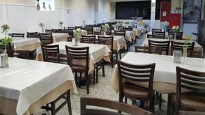 Comedor con varias mesas y sillas dispuestas en filas.