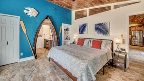 Ein Schlafzimmer mit einem großen Bett, einer Holzzieldecke und einer blauen Akzentwand.
