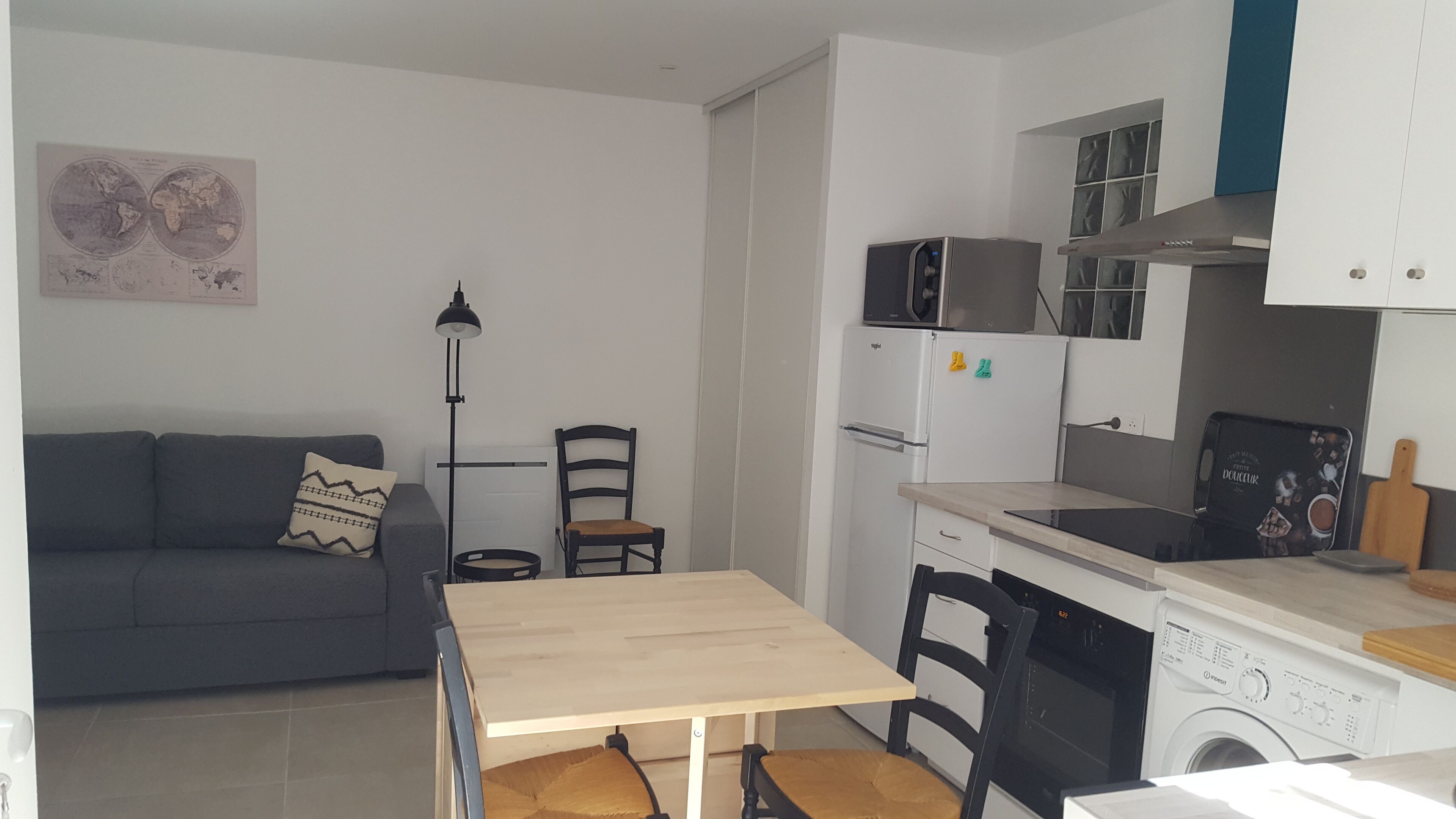 Een kleine keuken met een eettafel, een bank, een lamp en een wasmachine.