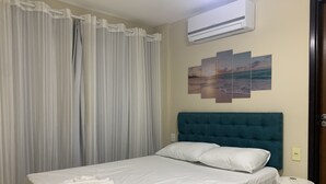Una cama bien hecha con sábanas blancas, un cabecero verde azulado y una almohada blanca.