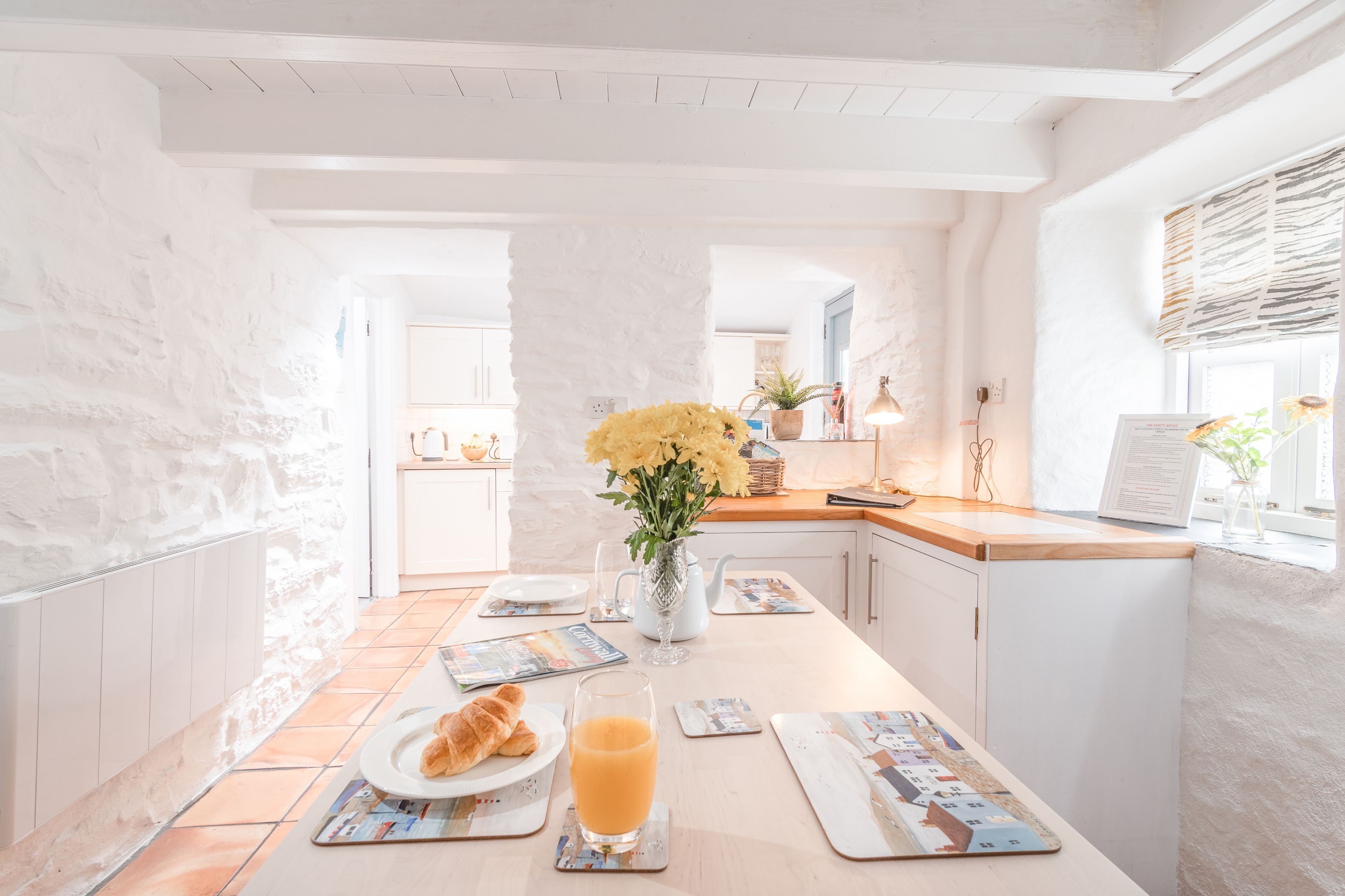 Ein Frühstückstisch mit Croissants, Orangensaft und einer Blumenvase.