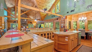 A wooden interior with a long dining table, wooden cabinets, and a kitchen area. - Now and Forever (Sevierville)