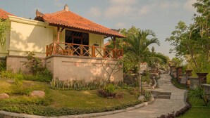 Eine traditionelle Villa mit Ziegeldach, einem Kiesweg und üppiger Vegetation.