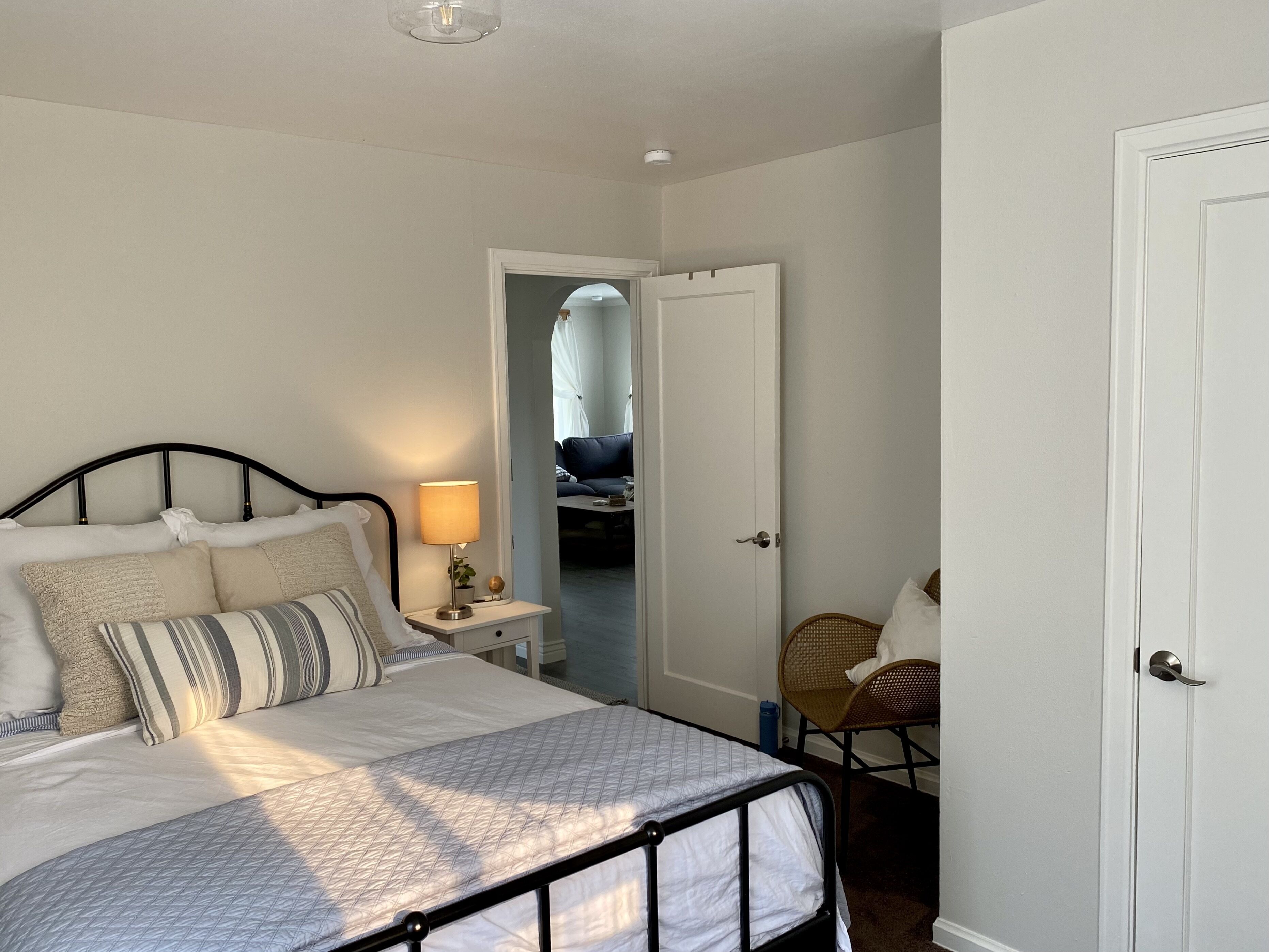 Een keurig opgemaakt slaapkamer met een bed, bedlamp en een stoel.
