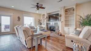 A spacious living room with a fireplace, comfortable seating, and a large TV. - Sea Esta- Front Row Views-4 bedroom 3-1/2 bath home, sleeps 12 guests. (Port Bolivar)