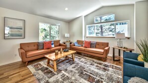 A modern living room with a brown leather sofa, a wooden coffee table, and a patterned rug.