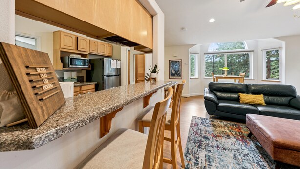 A modern kitchen with wooden cabinets, a granite countertop, and a bar area.
