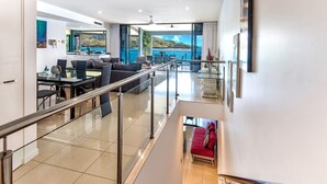 A modern interior with a staircase leading to a balcony with a scenic view.