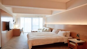 A modern hotel room with a large bed, a desk, and a chair. There is a TV mounted on the wall and a window with blinds. - Palace In Moon Beach (Onna)