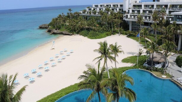 A resort with a beach, a pool, and a hotel building. - Palace In Moon Beach (Onna)