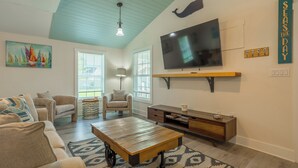 A living room with a large TV, a sofa, a coffee table, and a chair. - Pet Friendly Linens Included Rehoboth Beach House Parking Mini Golf (Rehoboth Beach)