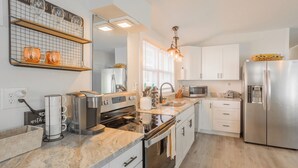 A modern kitchen with white cabinetry, stainless steel appliances, and a marble countertop. - Pet Friendly Linens Included Rehoboth Beach House Parking Mini Golf (Rehoboth Beach)