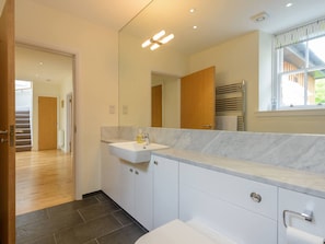 Un baño moderno con un lavamanos blanco, un espejo grande y una ventana.