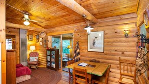 Un interior de cabaña acogedor con una mesa de comedor de madera, sillas, un sofá y una chimenea.