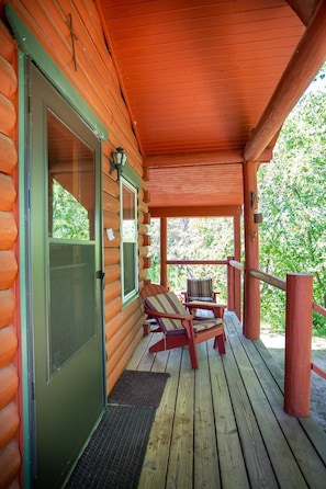 A log cabin with a covered porch, two chairs, and a bench. - Plover Retreat - Cute Cabin Close to Town, 5 min. from beach (Grand Marais)