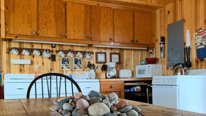 Un interior de madera con una zona de cocina que incluye armarios, un microondas y una estufa.
