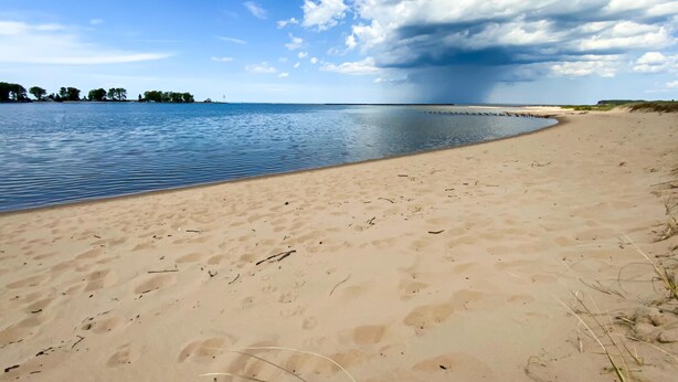 Una playa con arena y agua tranquila.