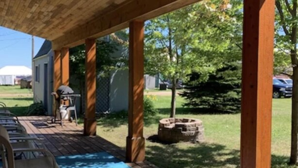 A wooden deck with a pool table, chairs, and a covered area with a view of the backyard. - Paul's Place - Two blocks from beaches in the heart of Grand Marais (Grand Marais)