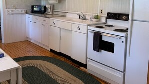A kitchen with white cabinets, a microwave, a stove, and a refrigerator. - Paul's Place - Two blocks from beaches in the heart of Grand Marais (Grand Marais)