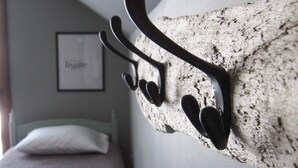 A room with a bed, a wall-mounted coat rack, and a framed picture. - Aspen House - Stunning 4 Bedroom A-Frame (Grand Marais)