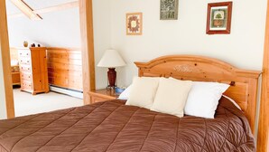 Un dormitorio con una cama de madera, una mesita de noche, una lámpara y un aparador.