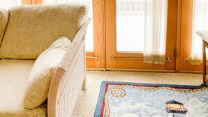 Una habitación acogedora con un sofá de mimbre, un mueble de madera y vistas a un lago a través de amplios ventanales.