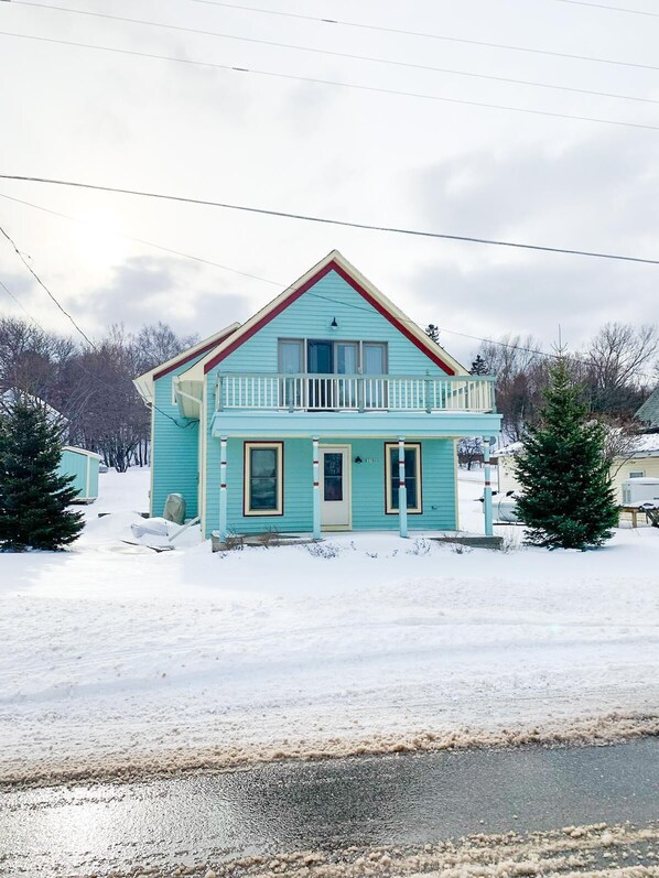 A two-story house with a balcony, surrounded by snow.
