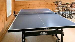 Una mesa de ping pong en una habitación con paredes de madera y techo inclinado.