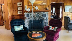 A cozy room with a stone fireplace, two armchairs, a small round table, and a lamp.