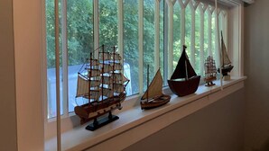 A window with multiple model ships displayed on a shelf.