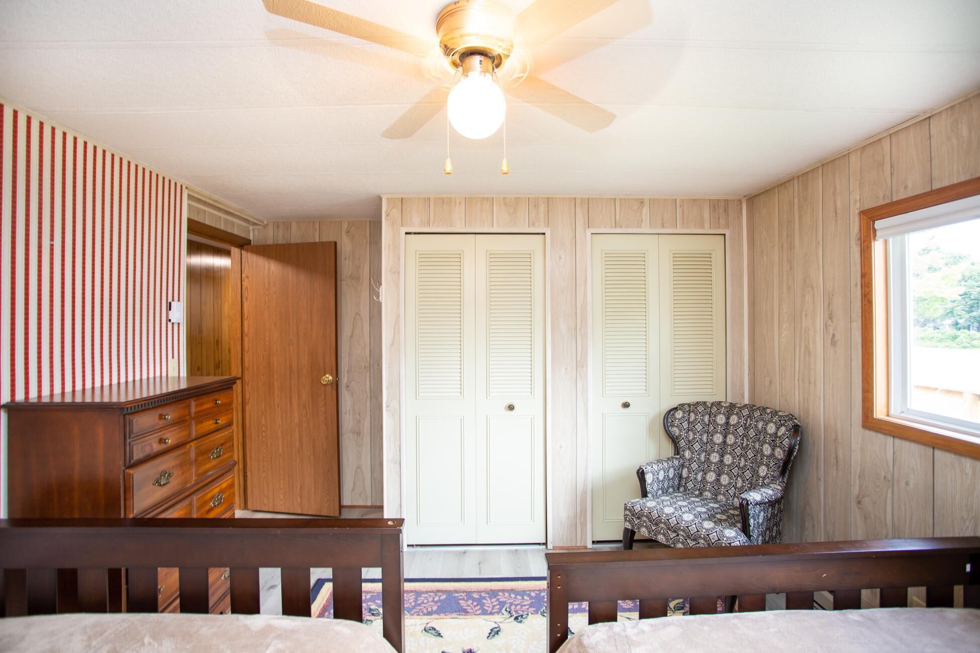 A bedroom with a bed, a dresser, a chair, and two doors.