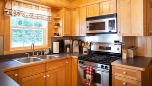 Une cuisine avec des meubles en bois, une cuisinière en acier inoxydable, un four à micro-ondes et un évier.