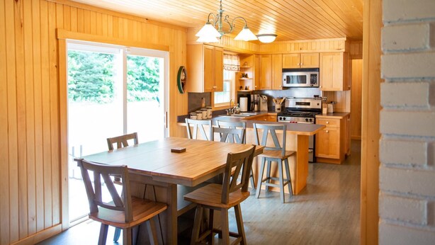 Un intérieur en bois comprenant un coin repas, une cuisine et une grande fenêtre.