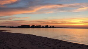 Ein Strand mit ruhigem Meer und einem Sonnenuntergangshimmel.