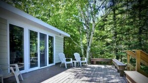 Eine Holterrasse mit Sitzgelegenheiten im Freien, darunter Stühle und eine Bank, umgeben von Bäumen.