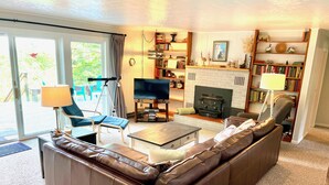 Ein Wohnzimmer mit braunem Ledersofa, einem Fernseher, einem Kamin und einem Bücherregal.
