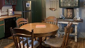 A kitchen with wooden cabinets, a dining table, chairs, a refrigerator, and a fireplace with decorative items.