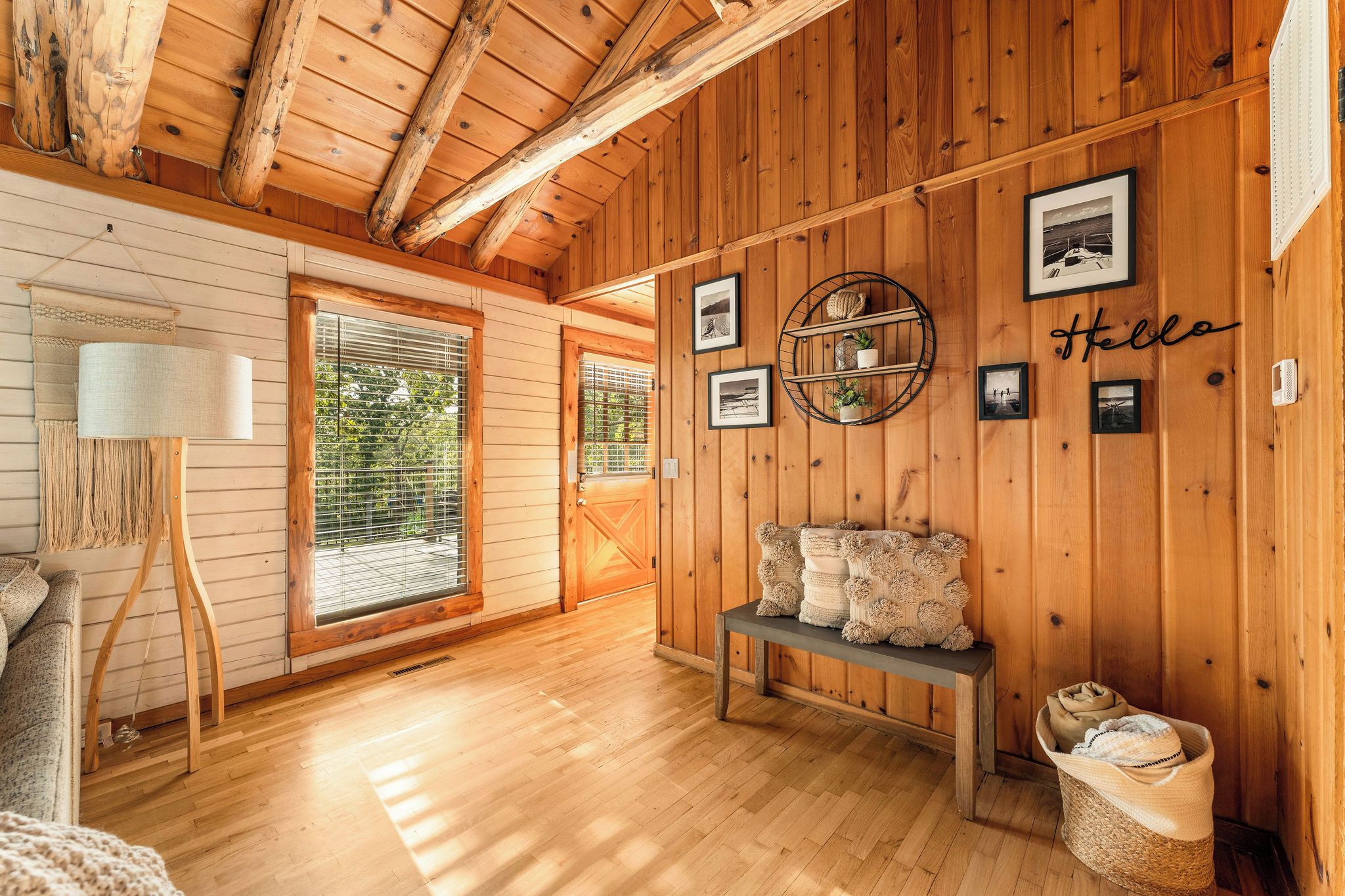 Una habitación acogedora con paredes de madera, un banco, una lámpara y cuadros enmarcados.