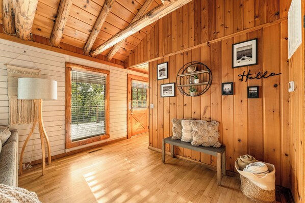 A cozy room with wooden walls, a bench, a lamp, and framed pictures.