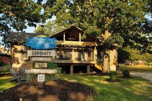 A lakeside cabin named 'Waterside Serenity' with a sign indicating 'Nightly Rental' and a website address. - Resort Cabin w/ Firepit, Spacious Deck & Outdoor TV - 2 Miles to SDC (Branson)
