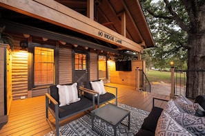 Uma cabana de toras com varanda, dois sofás, uma mesa e uma lareira.