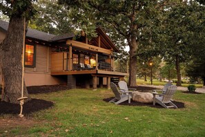 A lodge with a porch, outdoor seating, and a view of the surrounding trees.