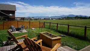 A backyard with a wooden deck, outdoor furniture, and a fire pit. - Bozeman Basecamp - Full House - Backyard (Bozeman)