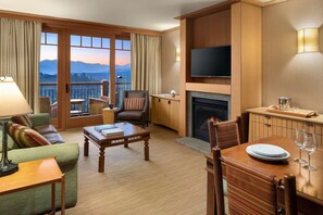 Ein Hotelzimmer mit Balkon, Kamin, Fernseher und Essbereich.