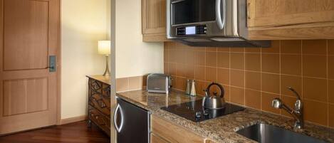 A kitchen with wooden cabinets, a stainless steel microwave, a sink, and a dishwasher.