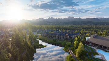A resort with a swimming pool, a bridge, and a mountain backdrop.