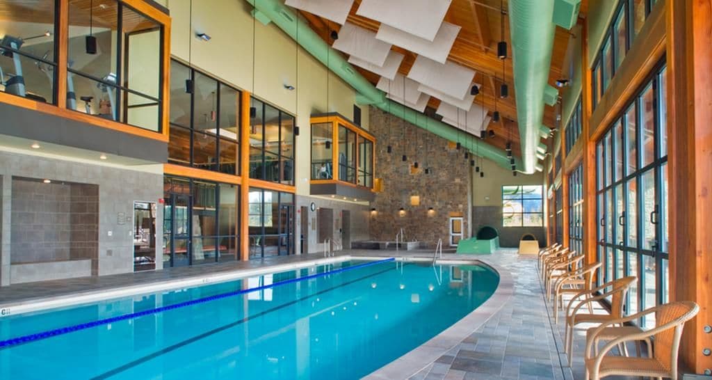 Ein Hallenbad mit freiem Blick auf den Poolbereich, einer Holzbalkendecke und großen Fenstern.