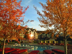 A hotel with a swimming pool, red lounge chairs, and autumn foliage. - Suncadia Resort (Cle Elum)