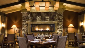 A dining area with a stone fireplace, wooden tables, and chairs. - Suncadia Resort (Cle Elum)