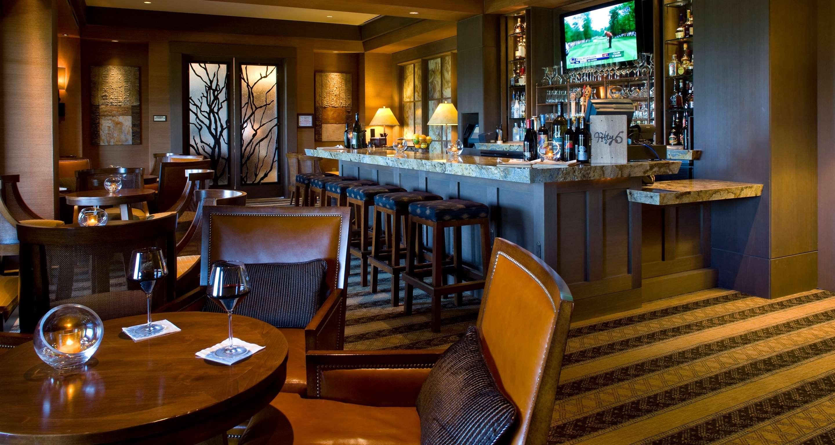 A bar area with a counter, stools, and a television screen displaying a golf game.